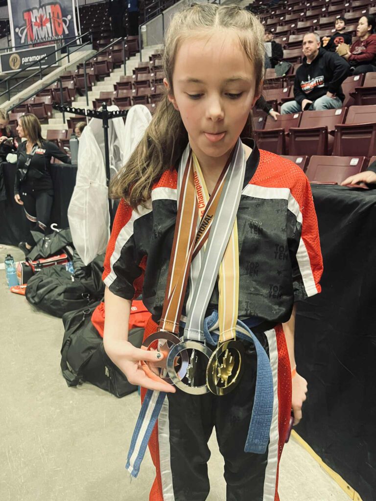 Student displaying medals achieved in competition representing Embrun Family Karate Club
